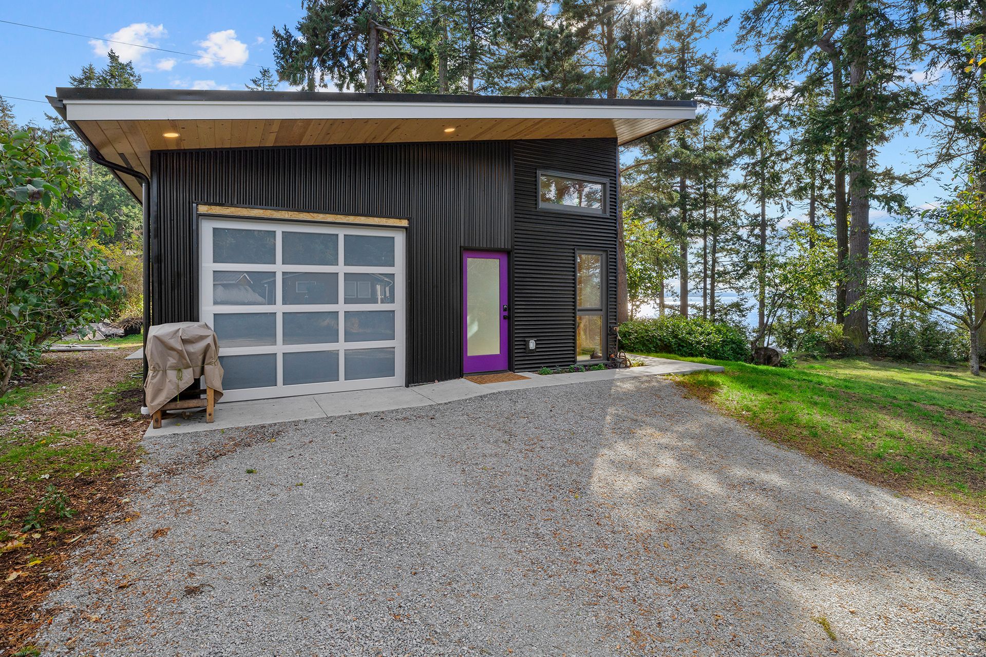 A small black house with a purple door and a garage.