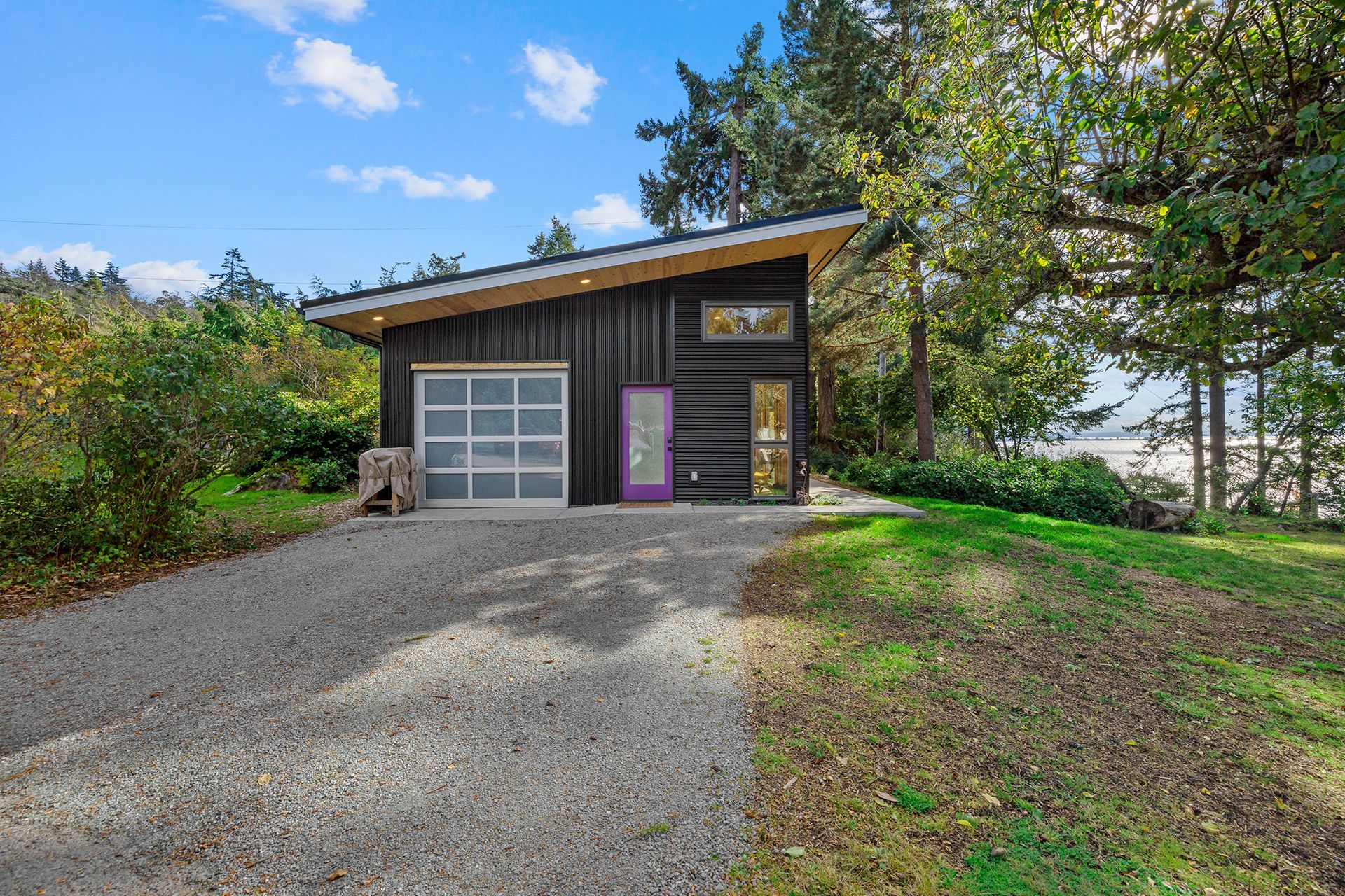 A small black house with a garage and a purple door.
