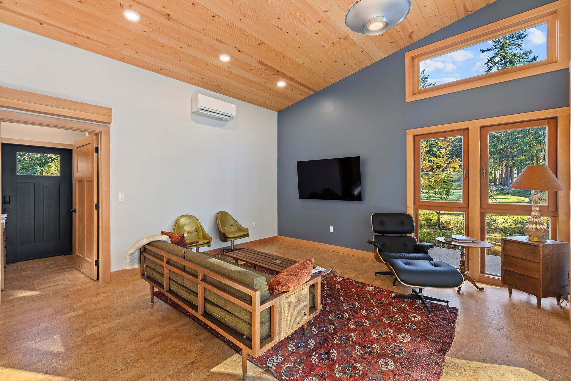 A living room with a couch and chairs and a flat screen tv on the wall.