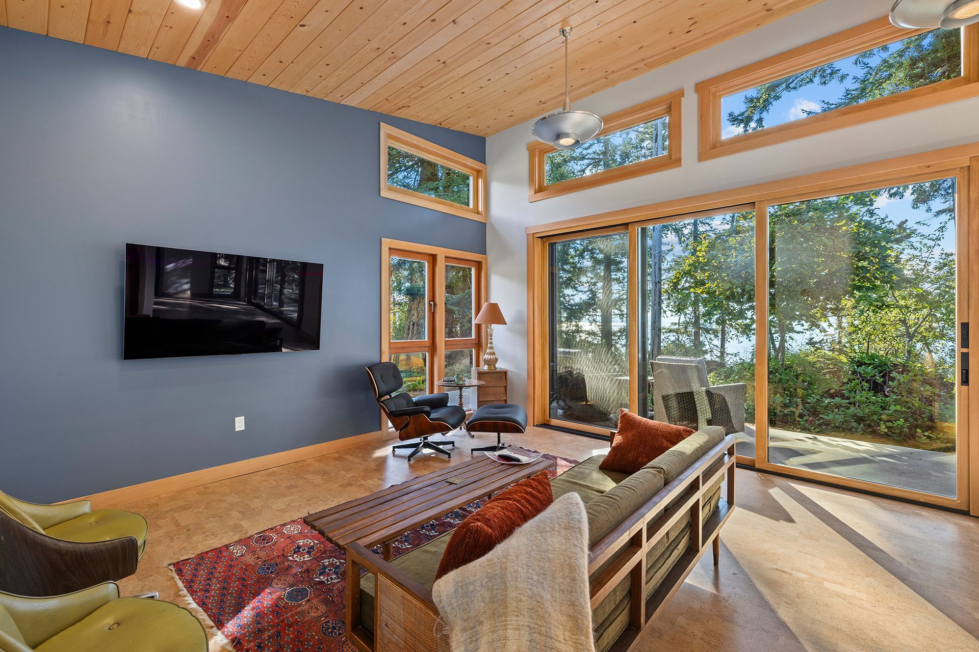 A living room with a couch and chairs and a flat screen tv on the wall.