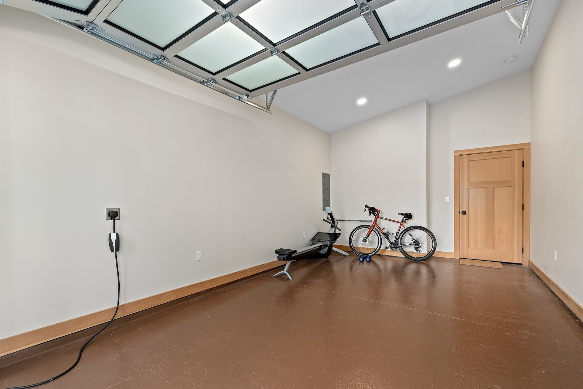 A bicycle is parked in a garage next to a rowing machine.