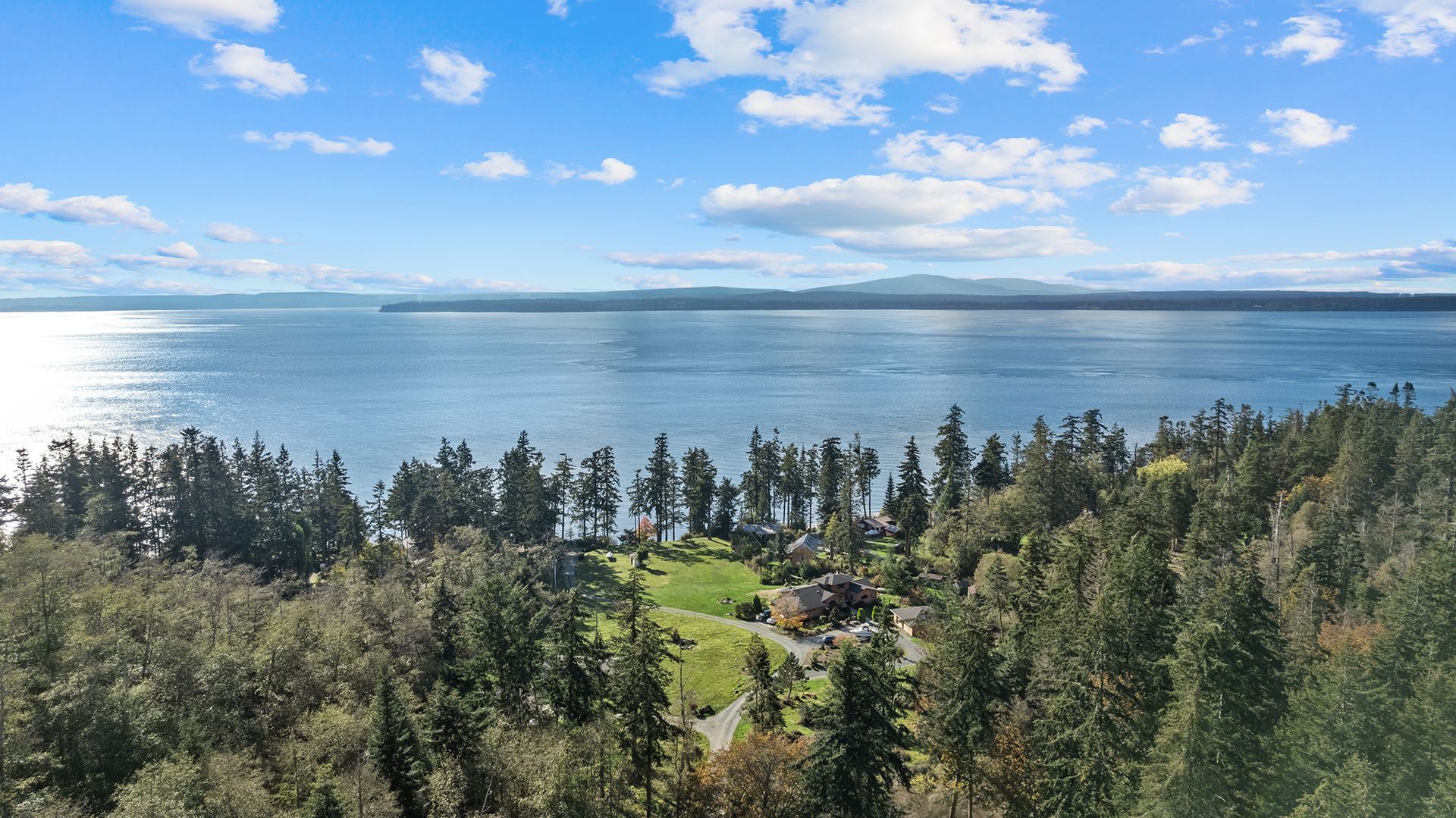 An aerial view of a lake surrounded by trees on a sunny day.