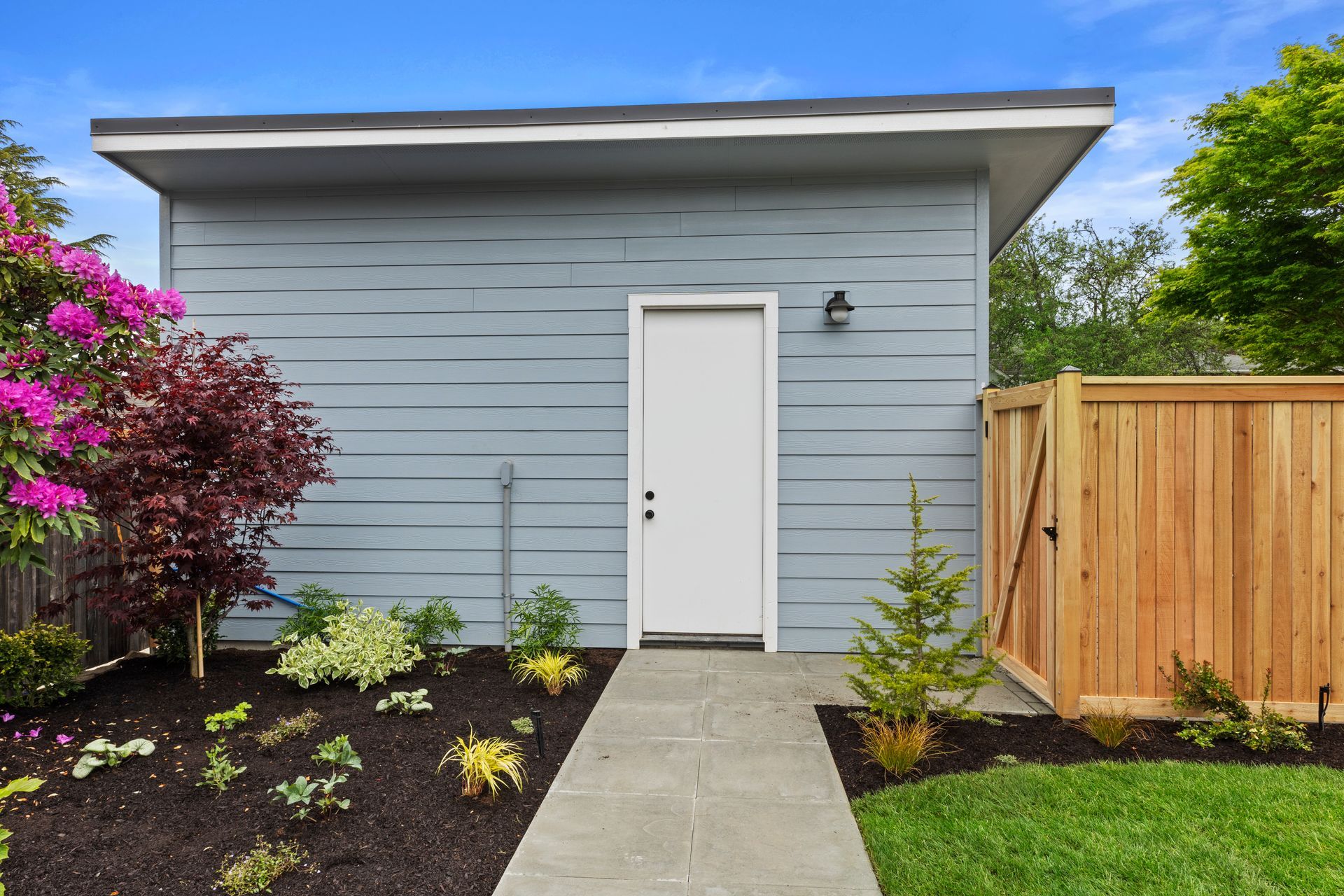 A small house with a white door and a wooden fence