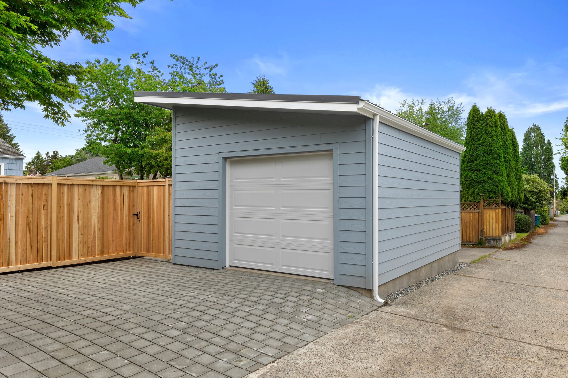 A small garage with a white door and a wooden fence in front of it.