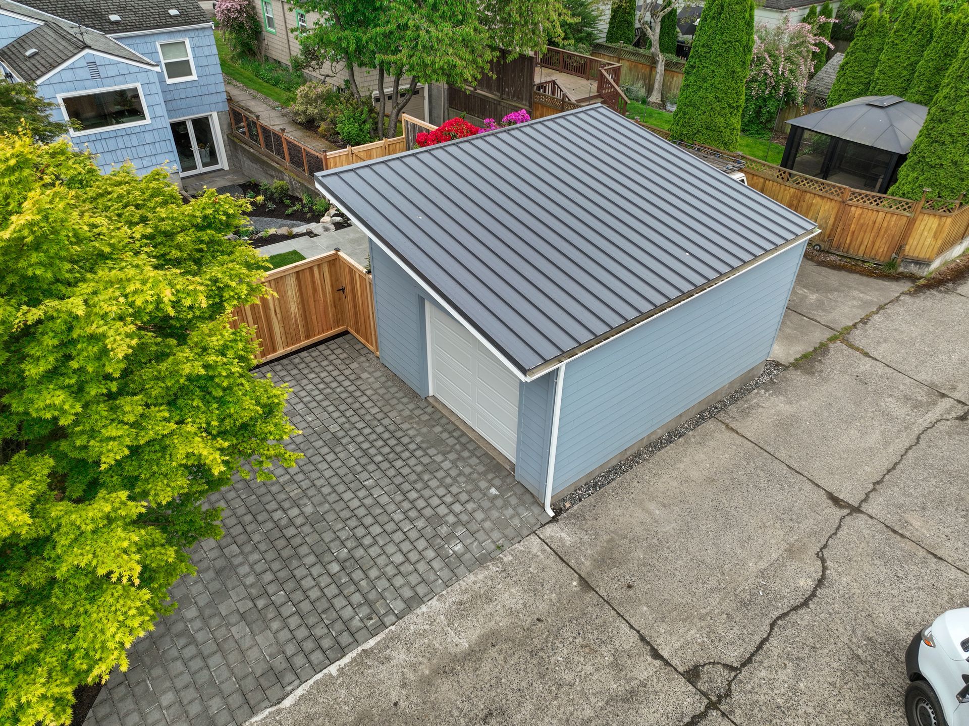 An aerial view of a garage with a metal roof and a car parked in front of it.