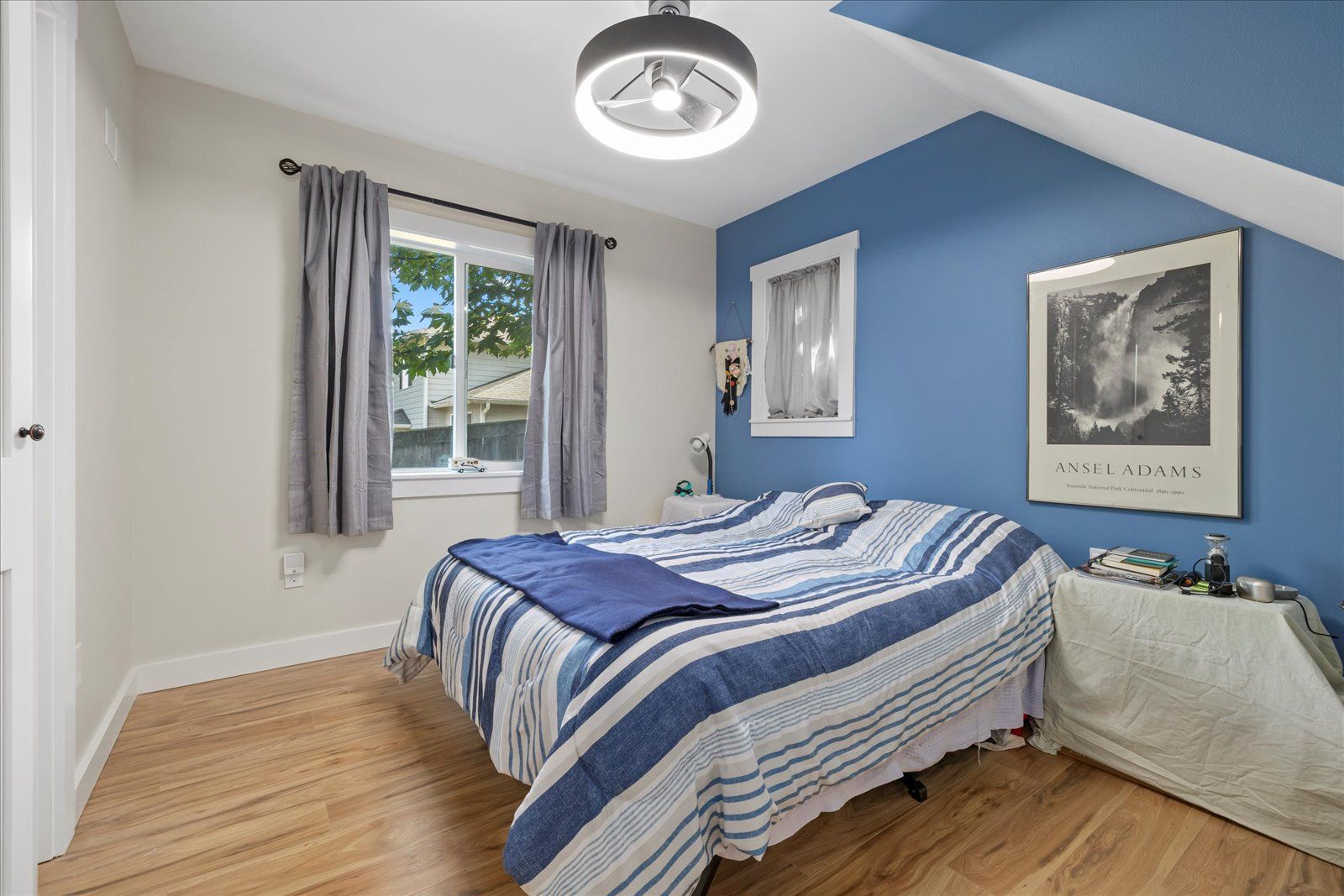 A bedroom with blue walls and a bed with a blue and white striped comforter.