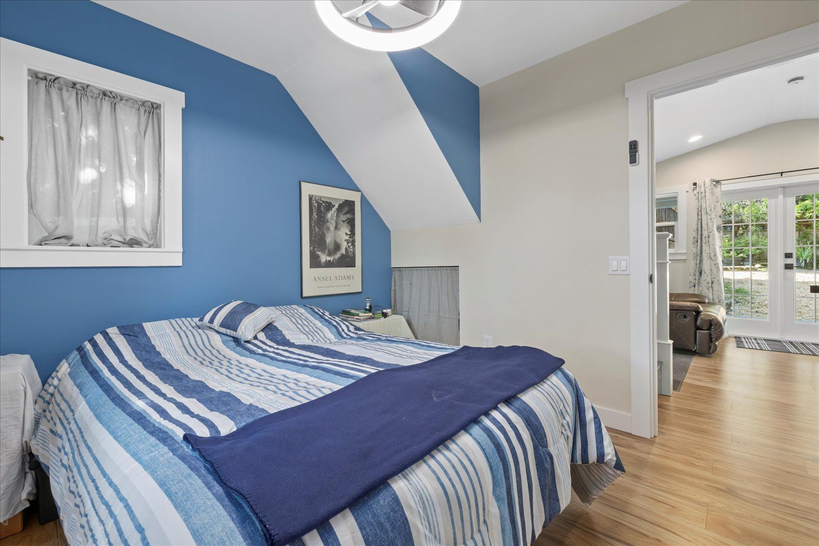 A bedroom with blue walls and a bed with a blue and white striped comforter.