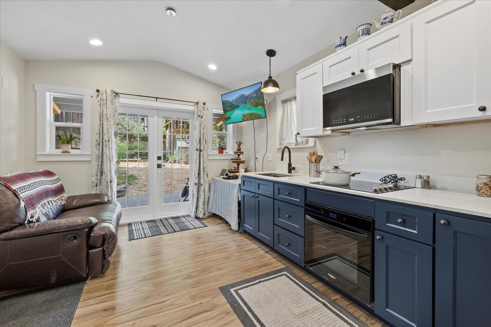 A kitchen with blue cabinets, white cabinets, and stainless steel appliances.