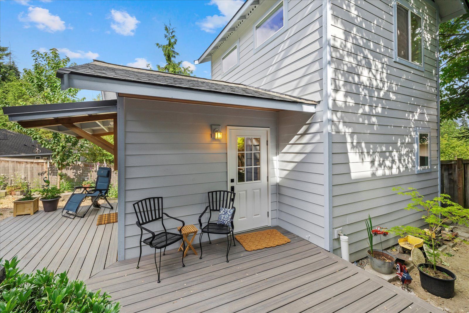 There is a deck with chairs and a table in front of a house.