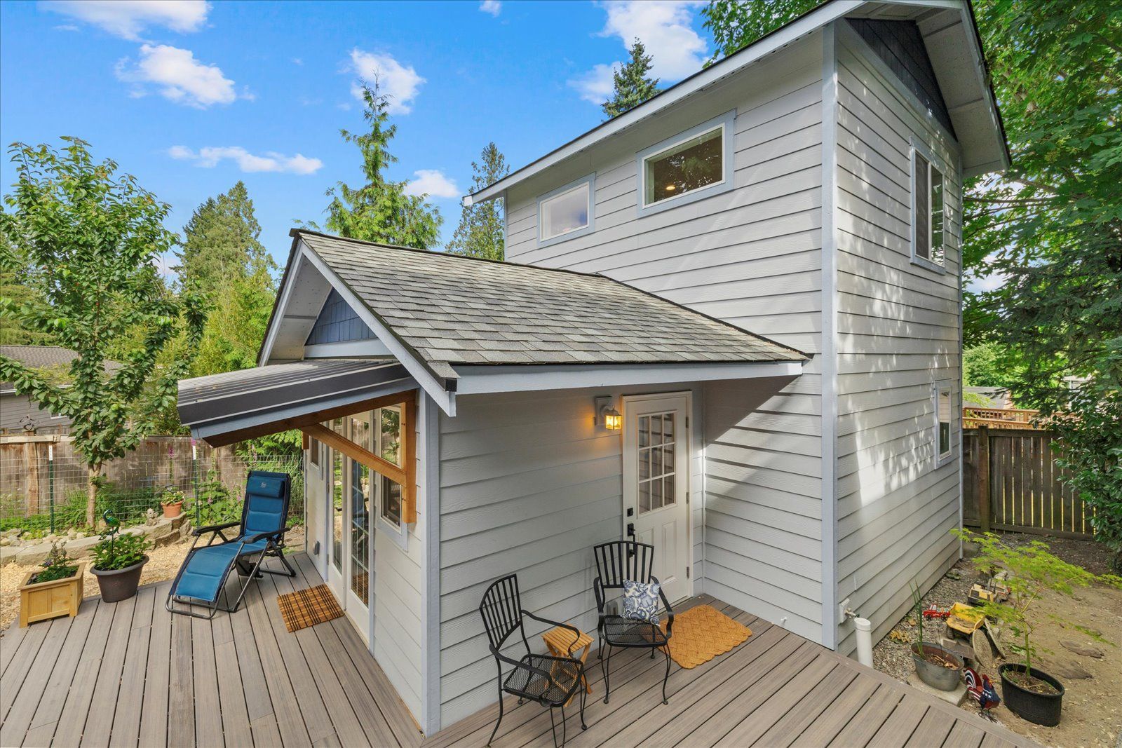 A small white house with a deck and chairs on it.