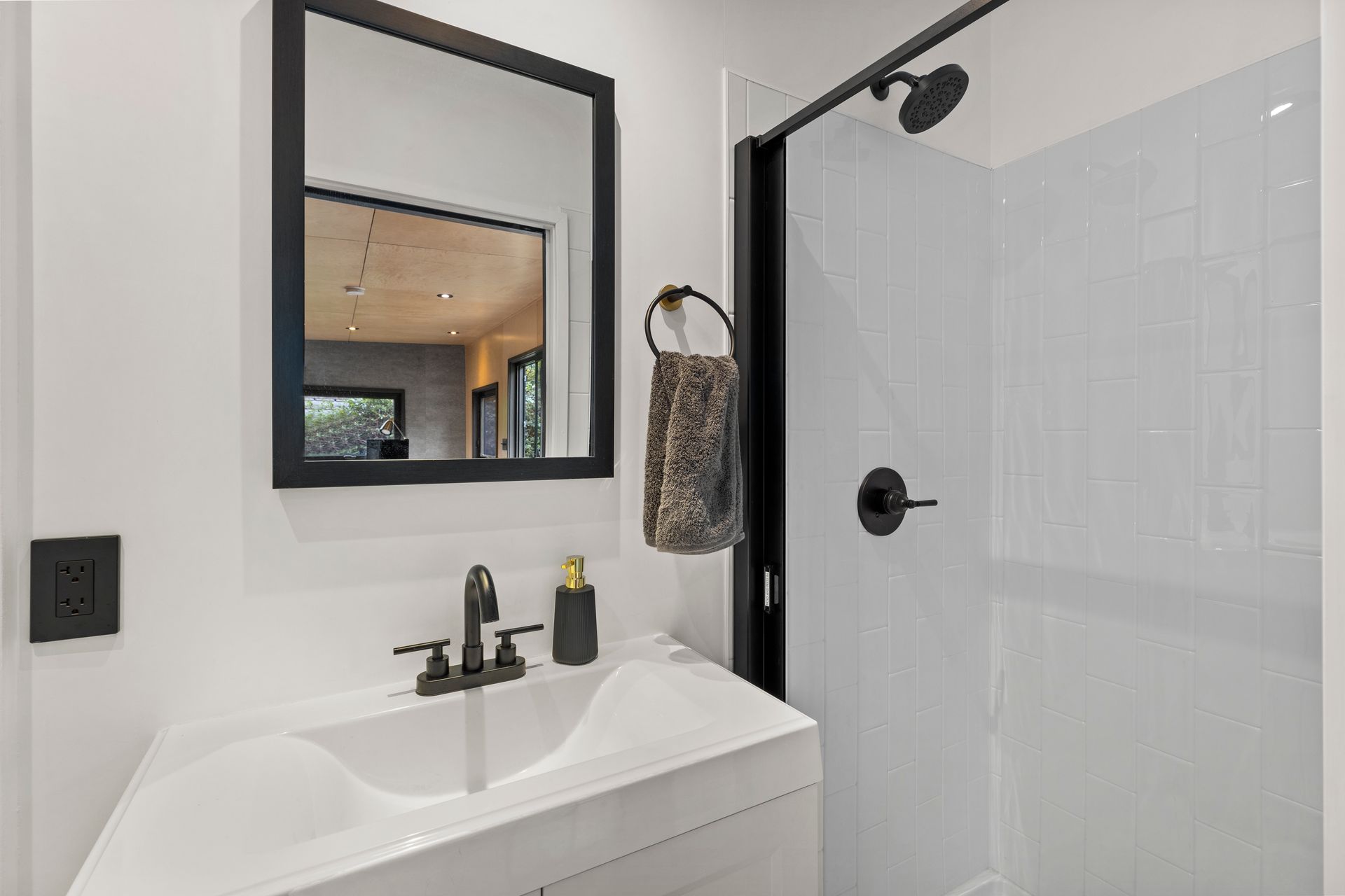 A bathroom with a sink, mirror, and shower.