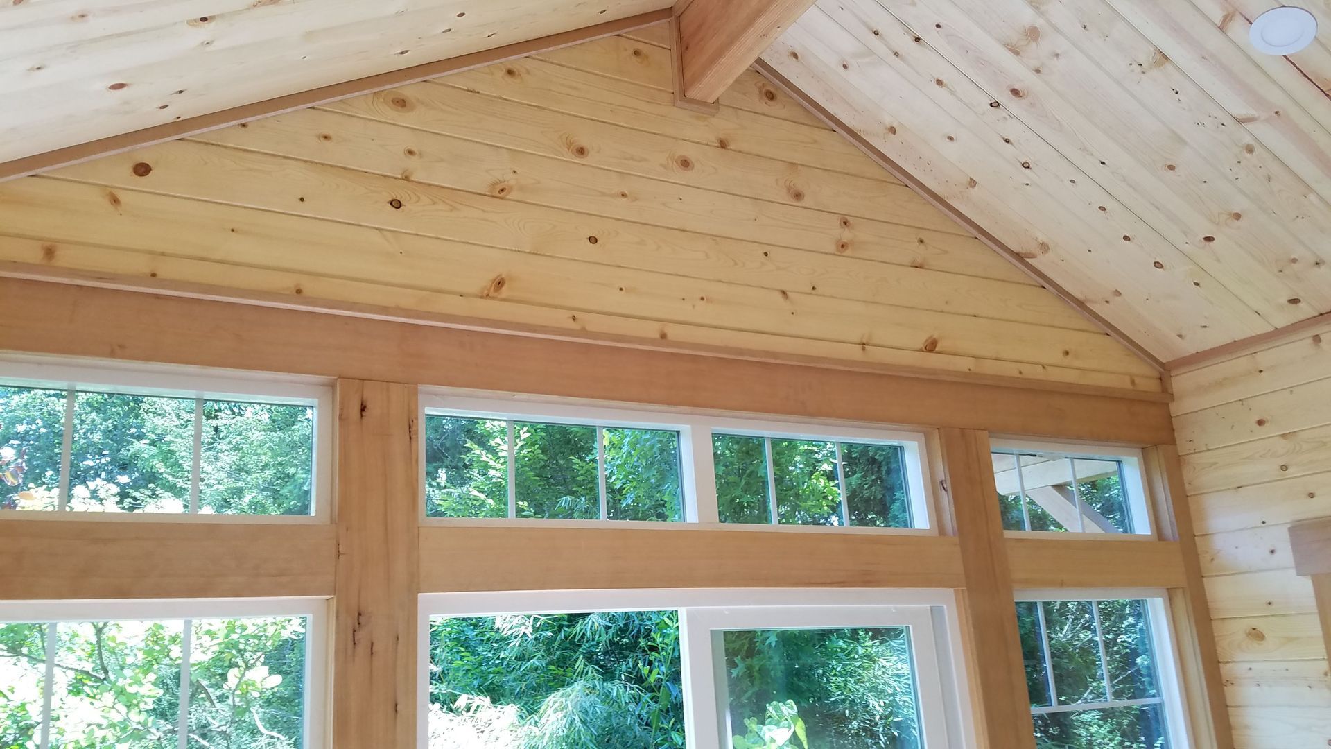 A room with a wooden ceiling and lots of windows.