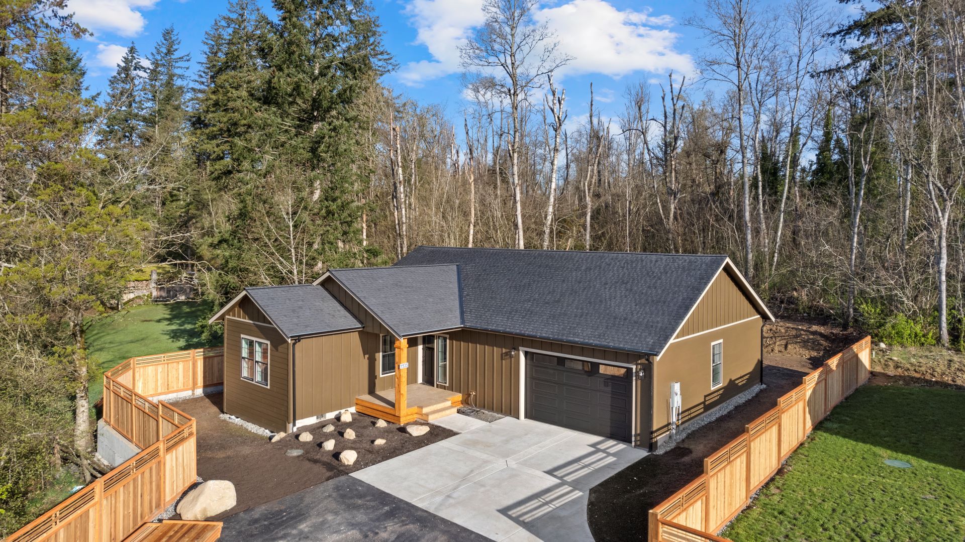 An aerial view of a house with a fence around it surrounded by trees.