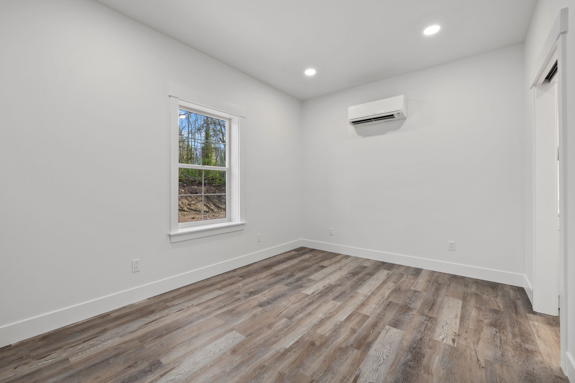 An empty room with hardwood floors and a window.