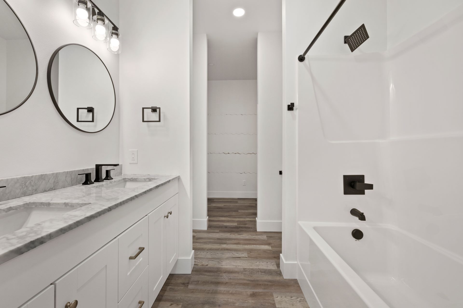A bathroom with two sinks , two mirrors , and a bathtub.