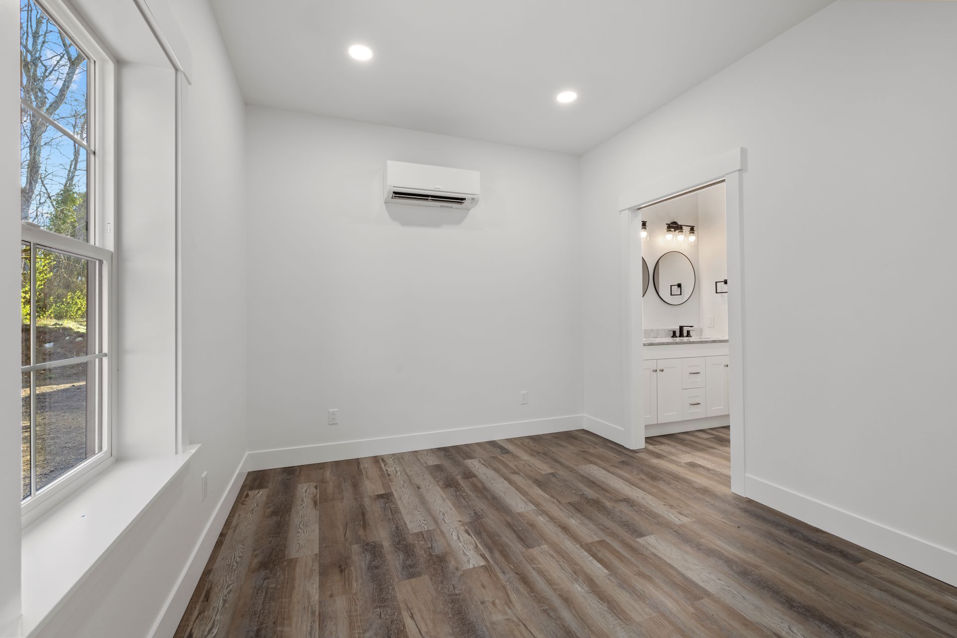 An empty room with hardwood floors and a window.