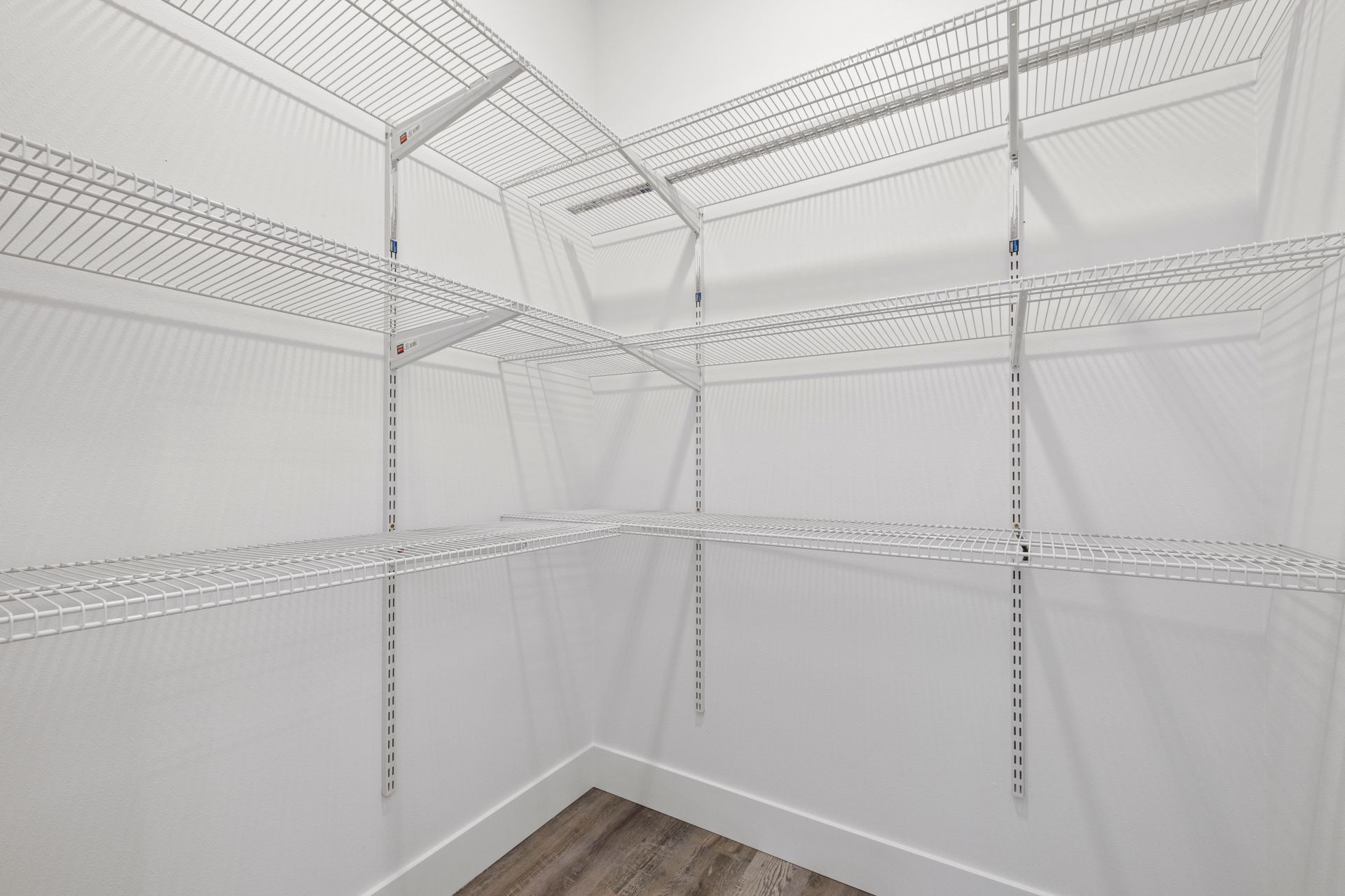 A walk in closet with lots of shelves and a wooden floor.