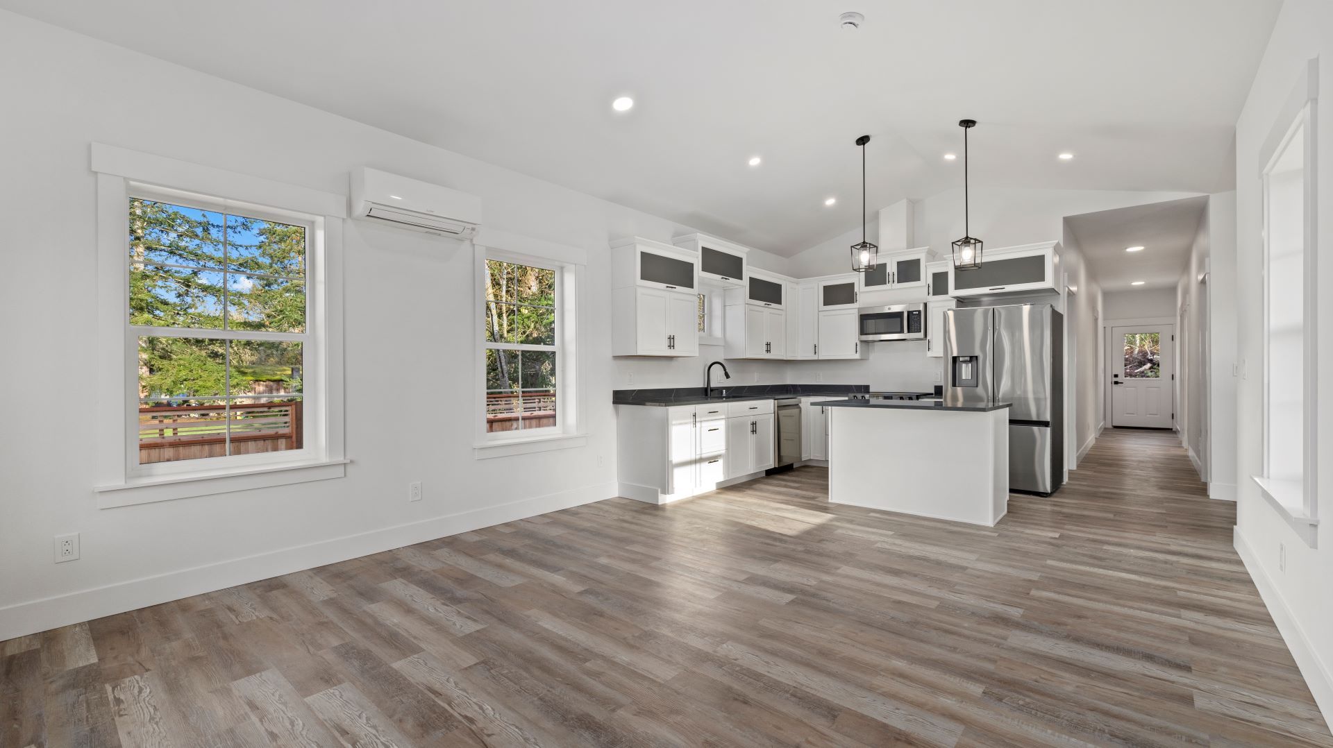 A large empty room with hardwood floors and a kitchen.
