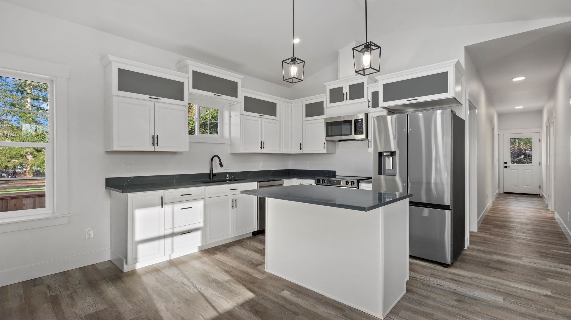 A kitchen with white cabinets , stainless steel appliances , and a large island.