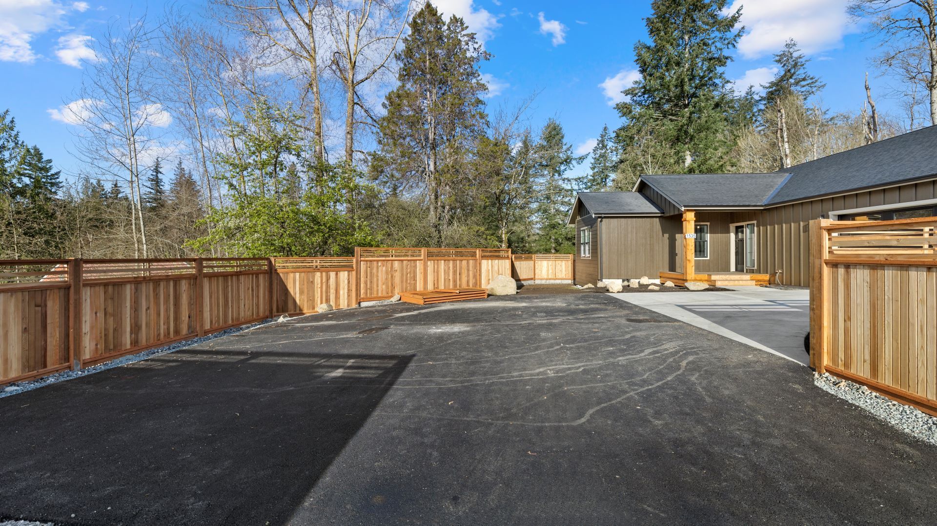 A driveway with a wooden fence and a house in the background