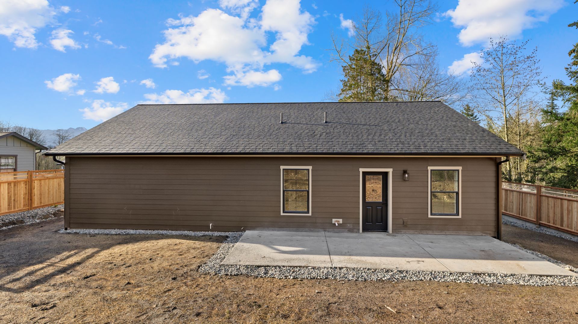 The back of a brown house with a black door and windows.