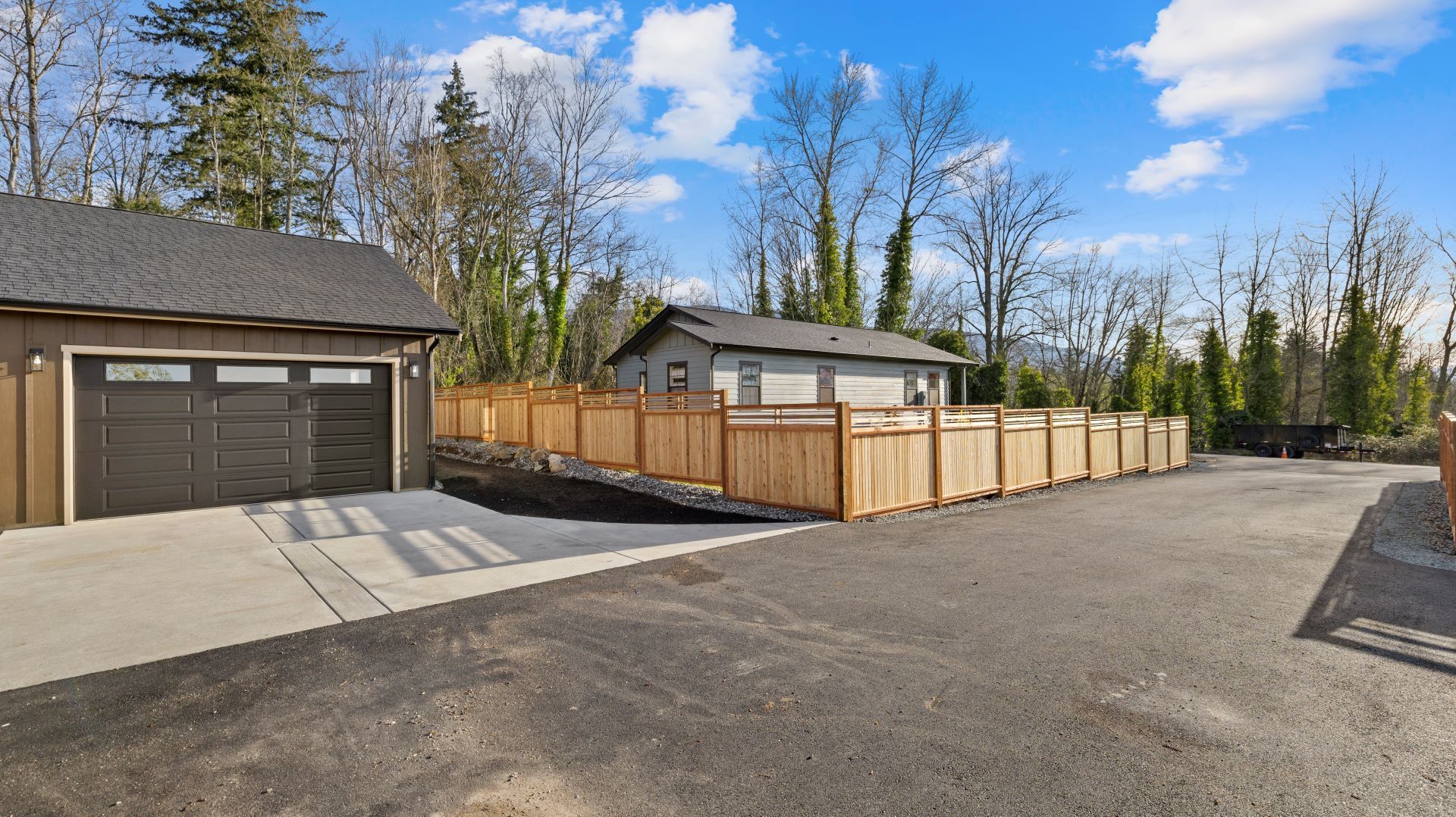 A house with a garage and a wooden fence in front of it.
