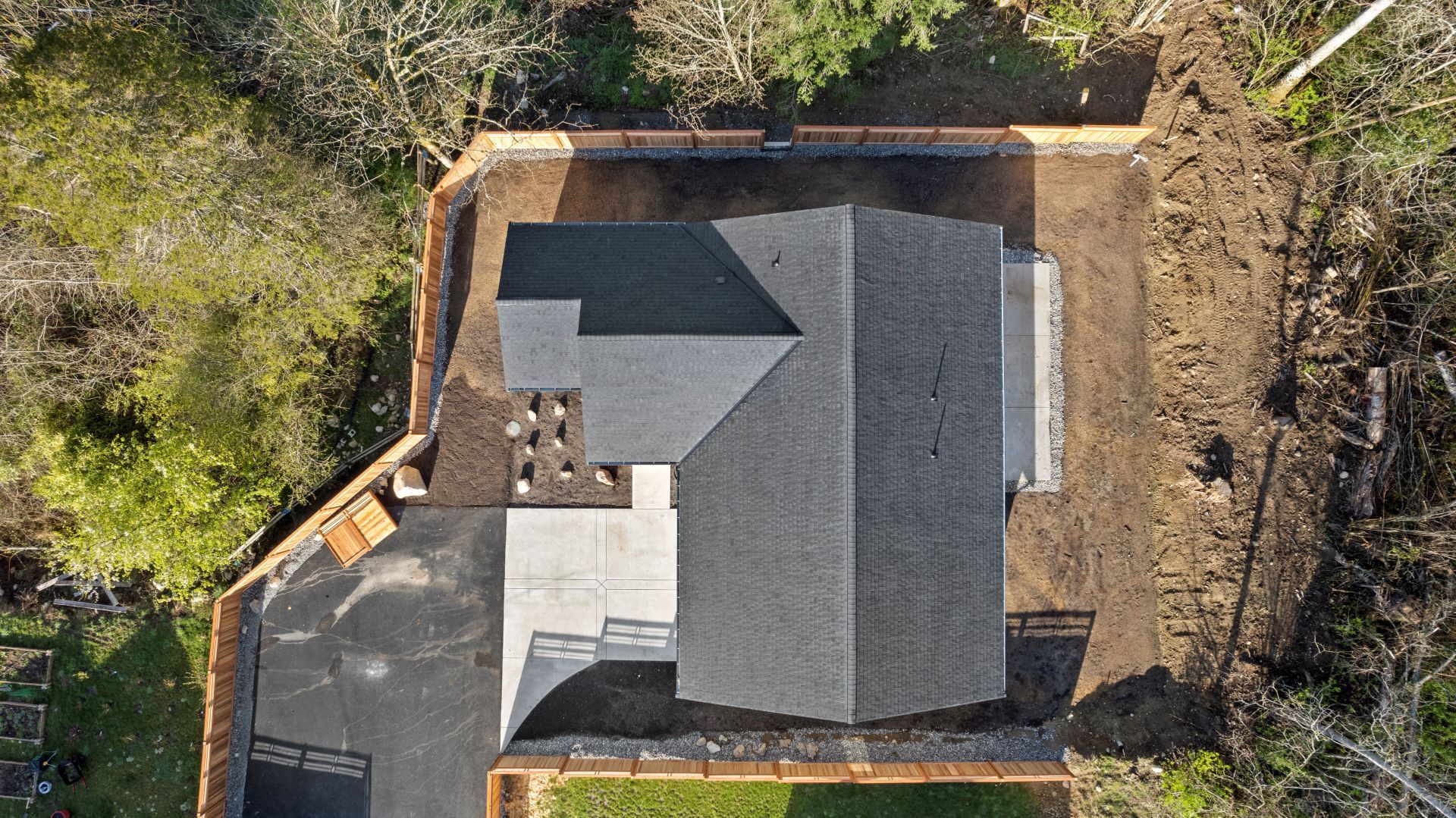 An aerial view of a house with a fence and trees in the background.