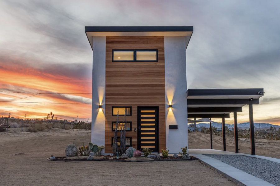 A small house with a wooden facade and a sunset in the background.
