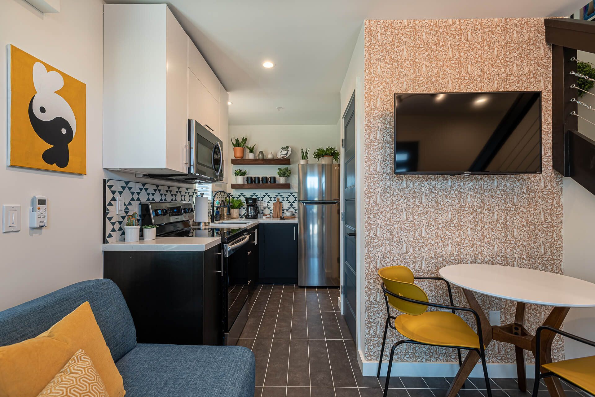 A living room with a couch, table, chairs, and a flat-screen tv.