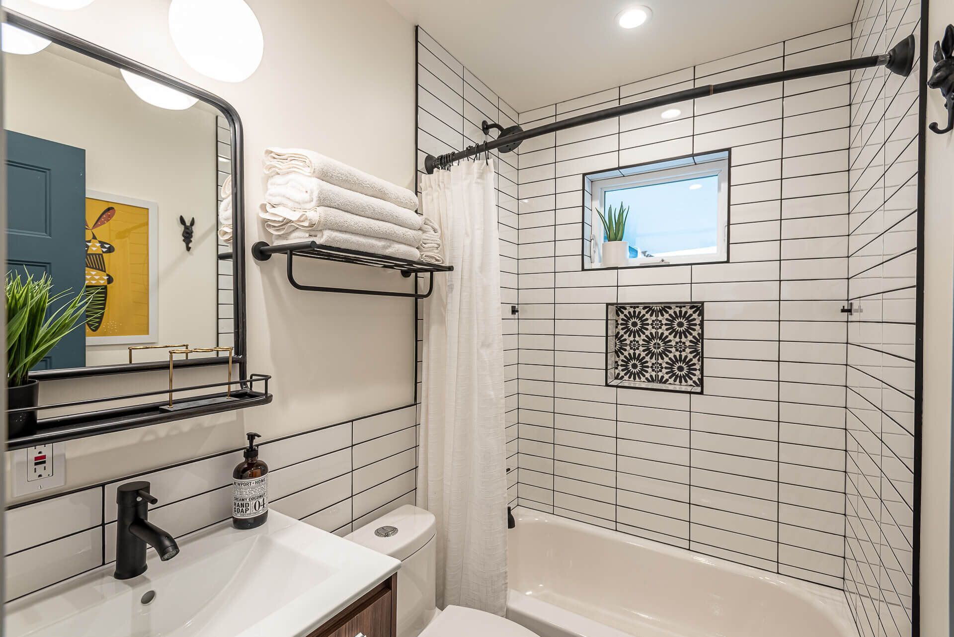 A bathroom with a sink, toilet, shower and mirror.