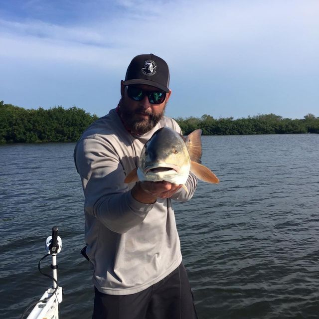 a man on a boat holding a large fish