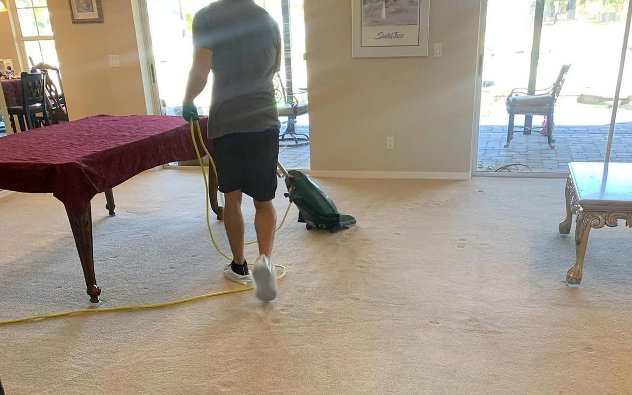 a man is cleaning a carpet in a living room with a vacuum cleaner.