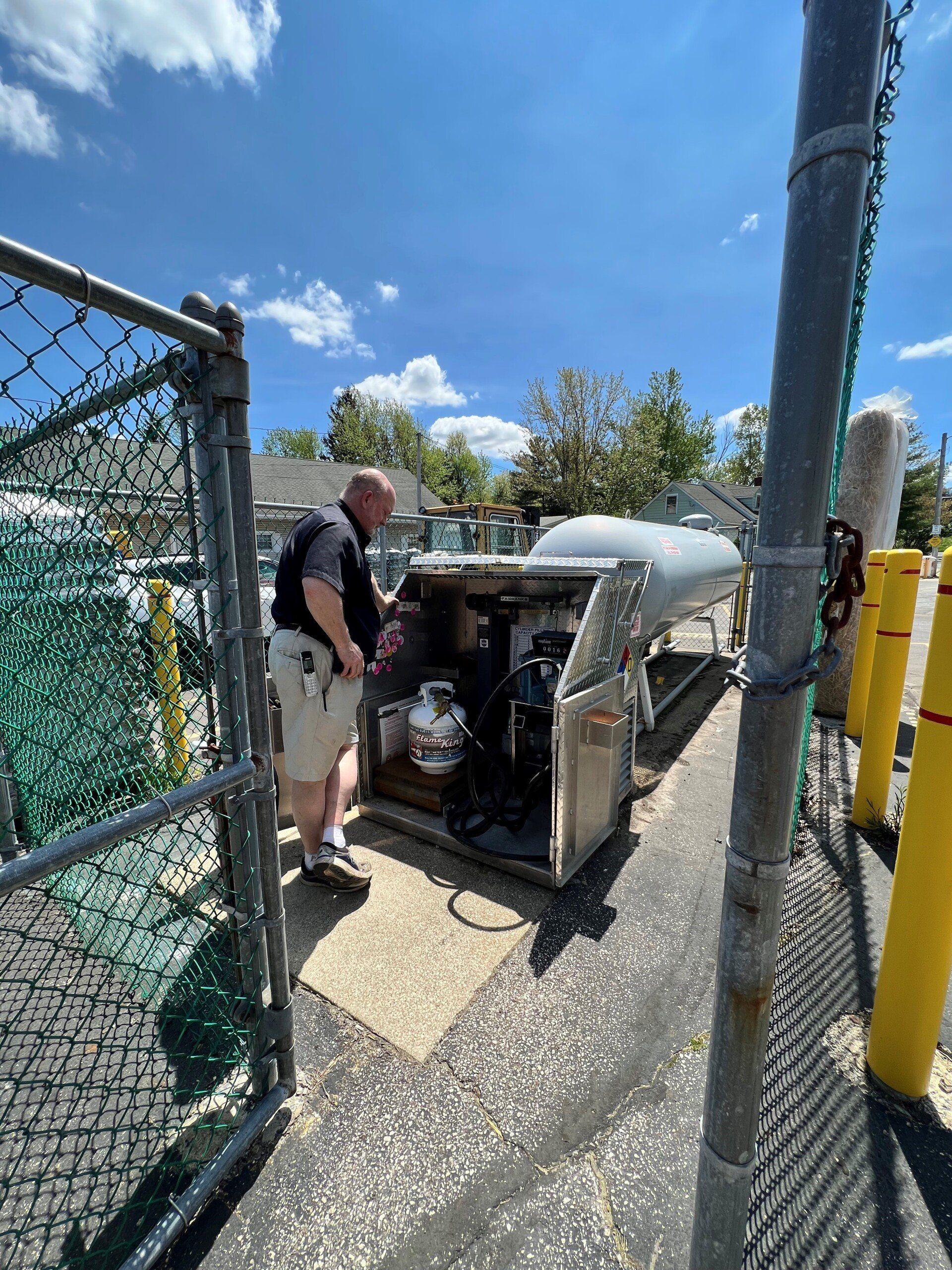 A man is standing next to a propane tank in a parking lot.