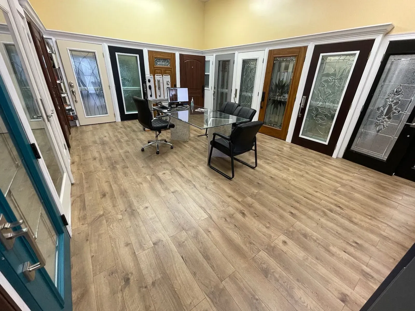 Showroom with various doors on display; light wood floors, office furniture.
