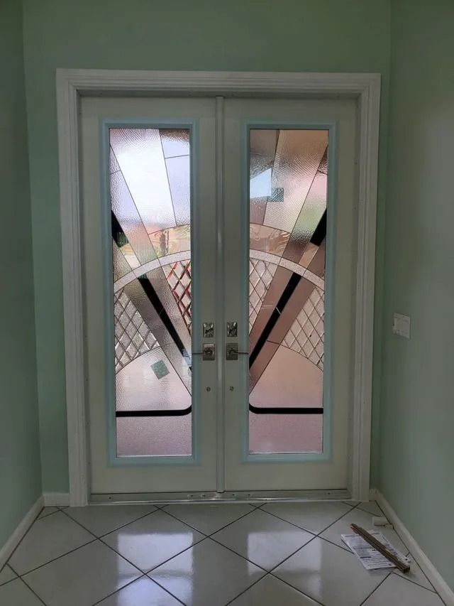 Double doors with art deco-style stained glass insets, installed in a light green entryway with tiled floors.