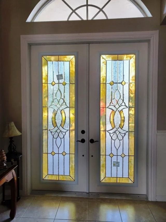 White double front doors with ornate leaded glass inserts and a semicircular transom window above.