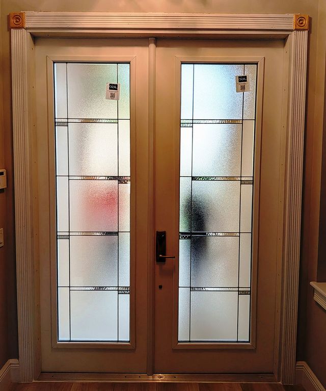 Double wooden frosted-glass front doors with a central handle and narrow side panels