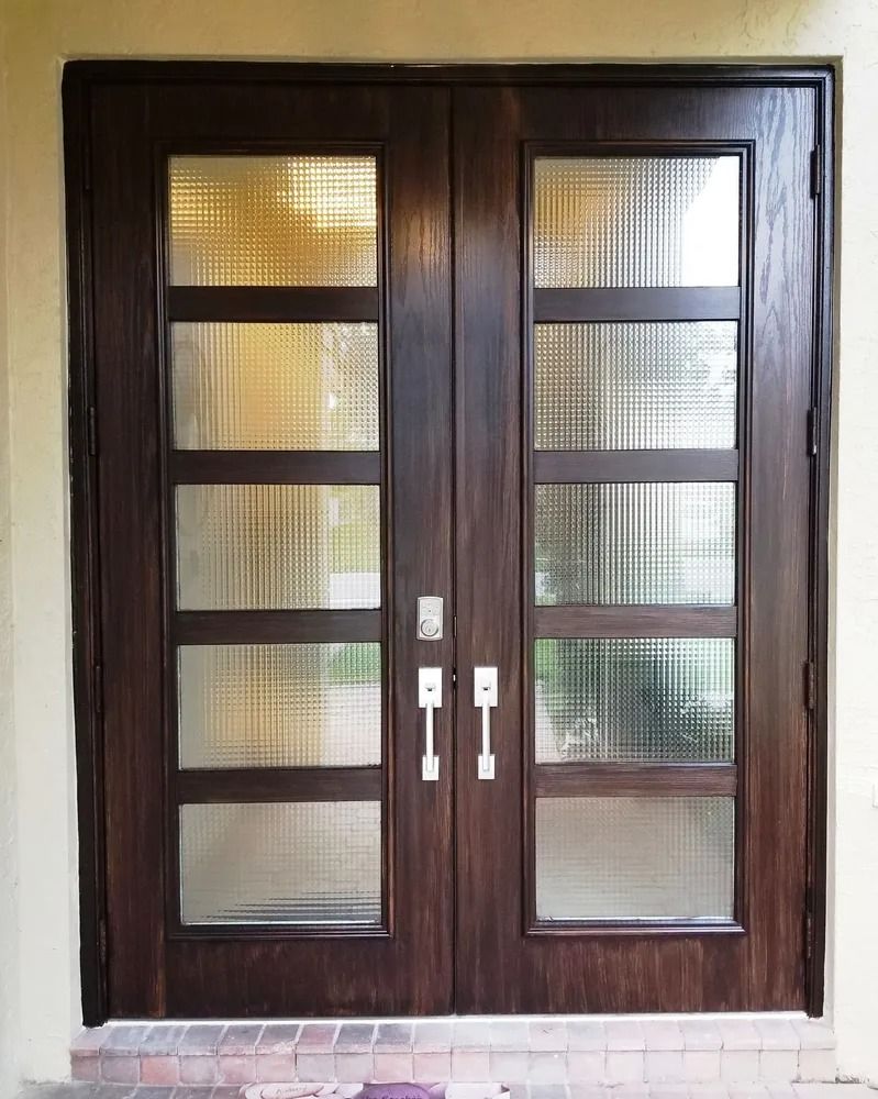 Double wooden front doors with textured glass panels, silver handles, and dark brown frames.