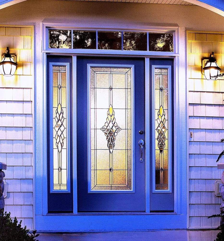 Blue front door with stained glass panels and sidelights, flanked by sconce lights.