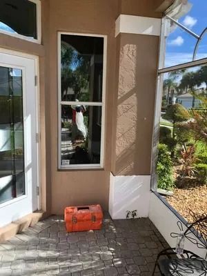 Tall window and door on a patio with a brick floor. Orange toolbox sits at the window.