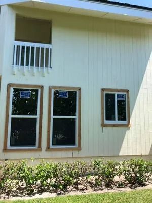 Exterior of a house with light yellow siding, three windows, and a balcony.