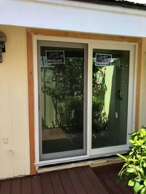Sliding glass door, beige siding, brown trim, and a dark wood deck.