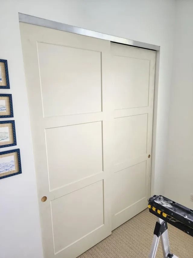 White paneled sliding closet doors in a room with a sawhorse and artwork.