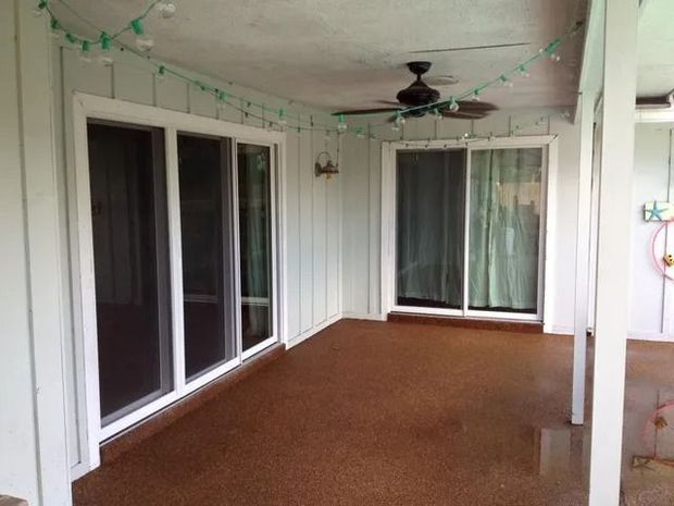 Covered patio with sliding glass doors, brown flooring, and green string lights.