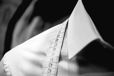 A white shirt is being measured with a tape measure