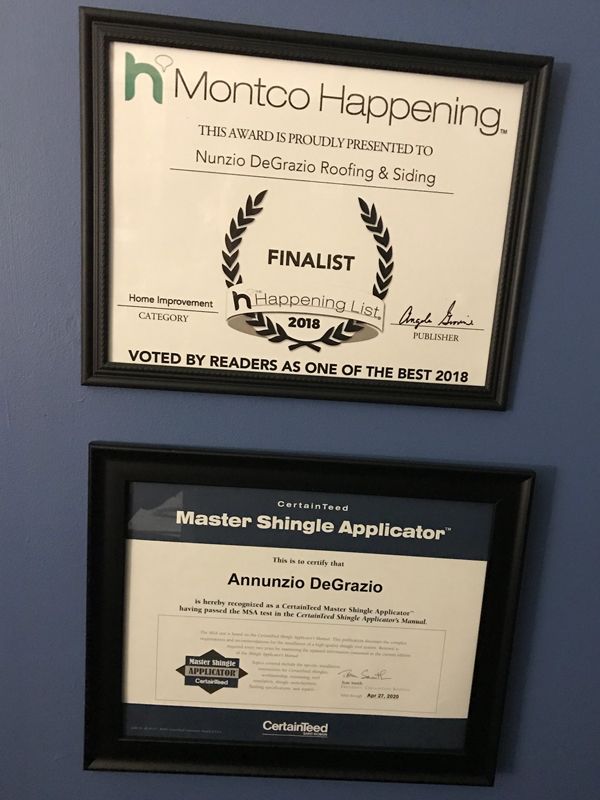 Two framed awards on a wall, including a Montco Happening finalist plaque and a Master Shingle Applicator certificate