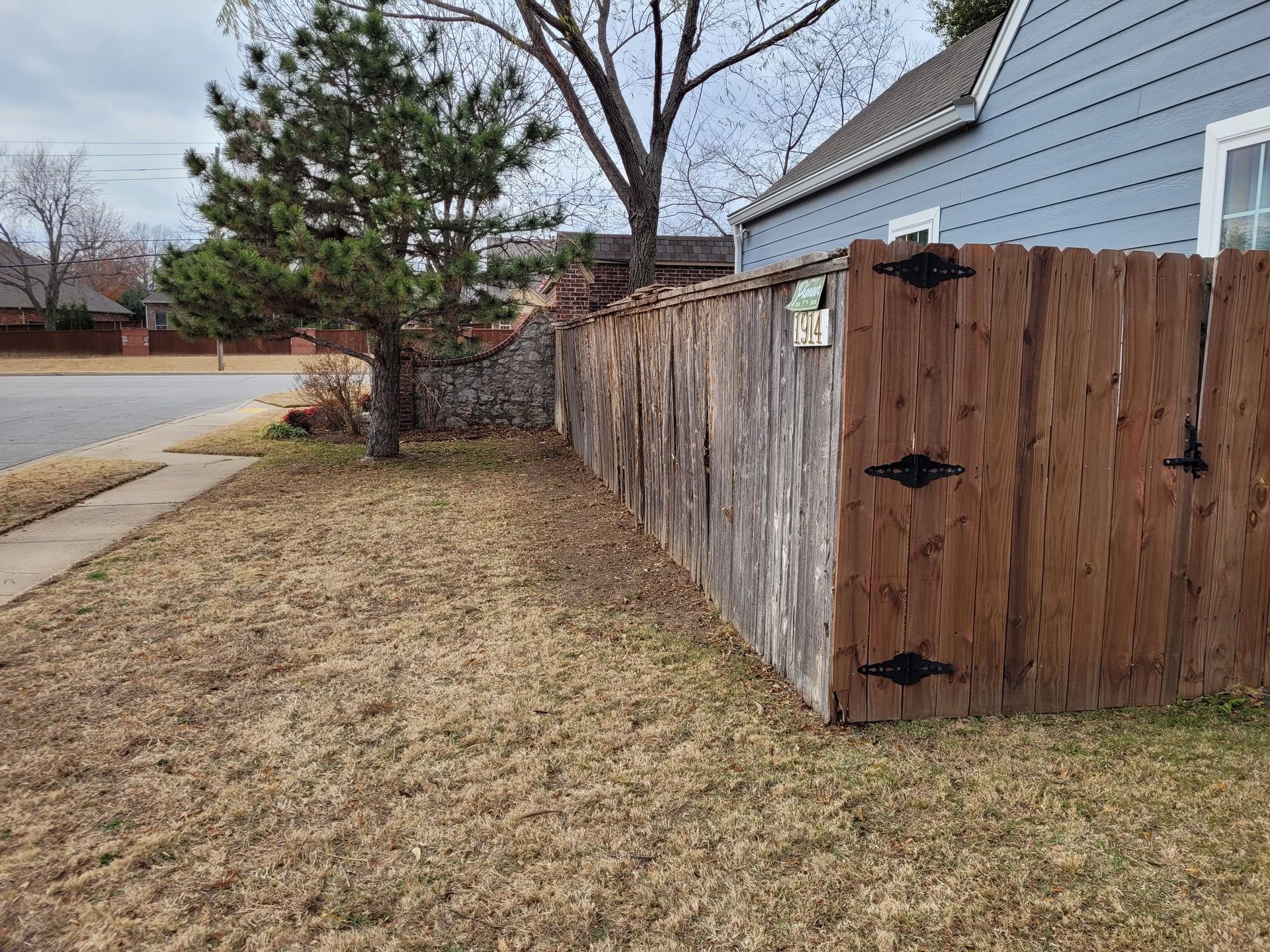after picture of a wooden fence in front of a blue house.