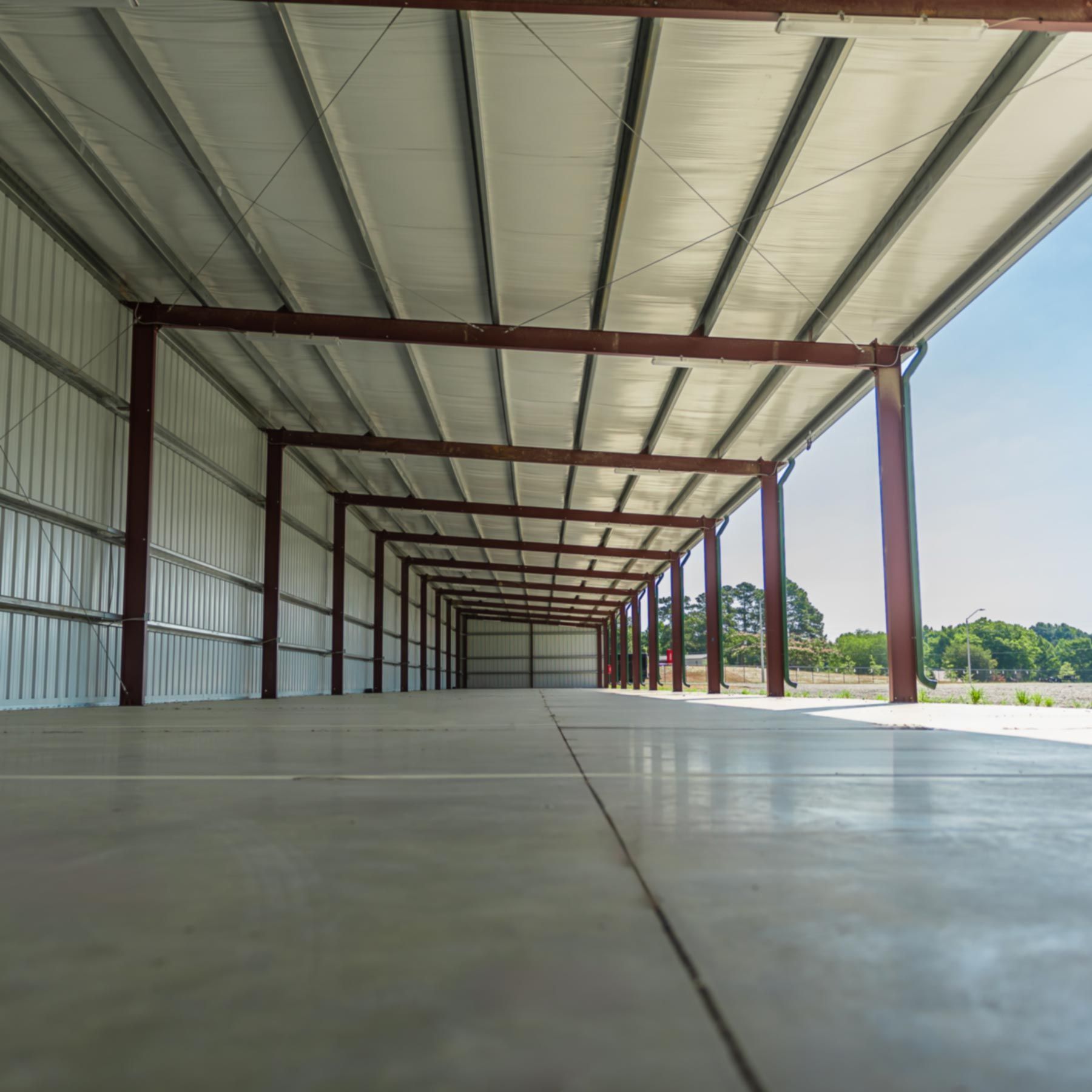 An empty warehouse with a concrete floor and a metal roof