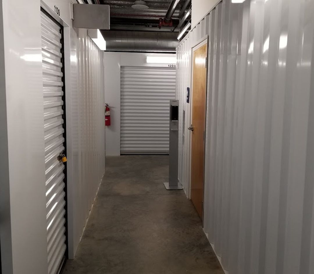 A long hallway in a building with a fire extinguisher on the wall.