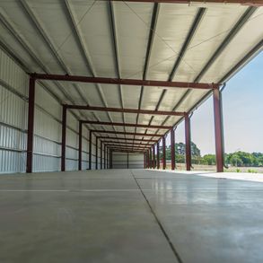 An empty warehouse with a concrete floor and a metal roof.